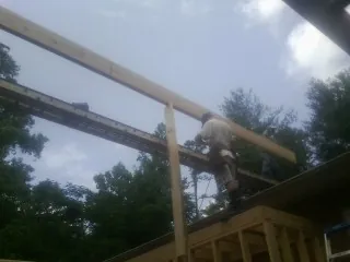 Carpenter setting a ridge beam over a new addition frame — Ice Dam Removal by Roofing Brothers in Cold Spring Harbor