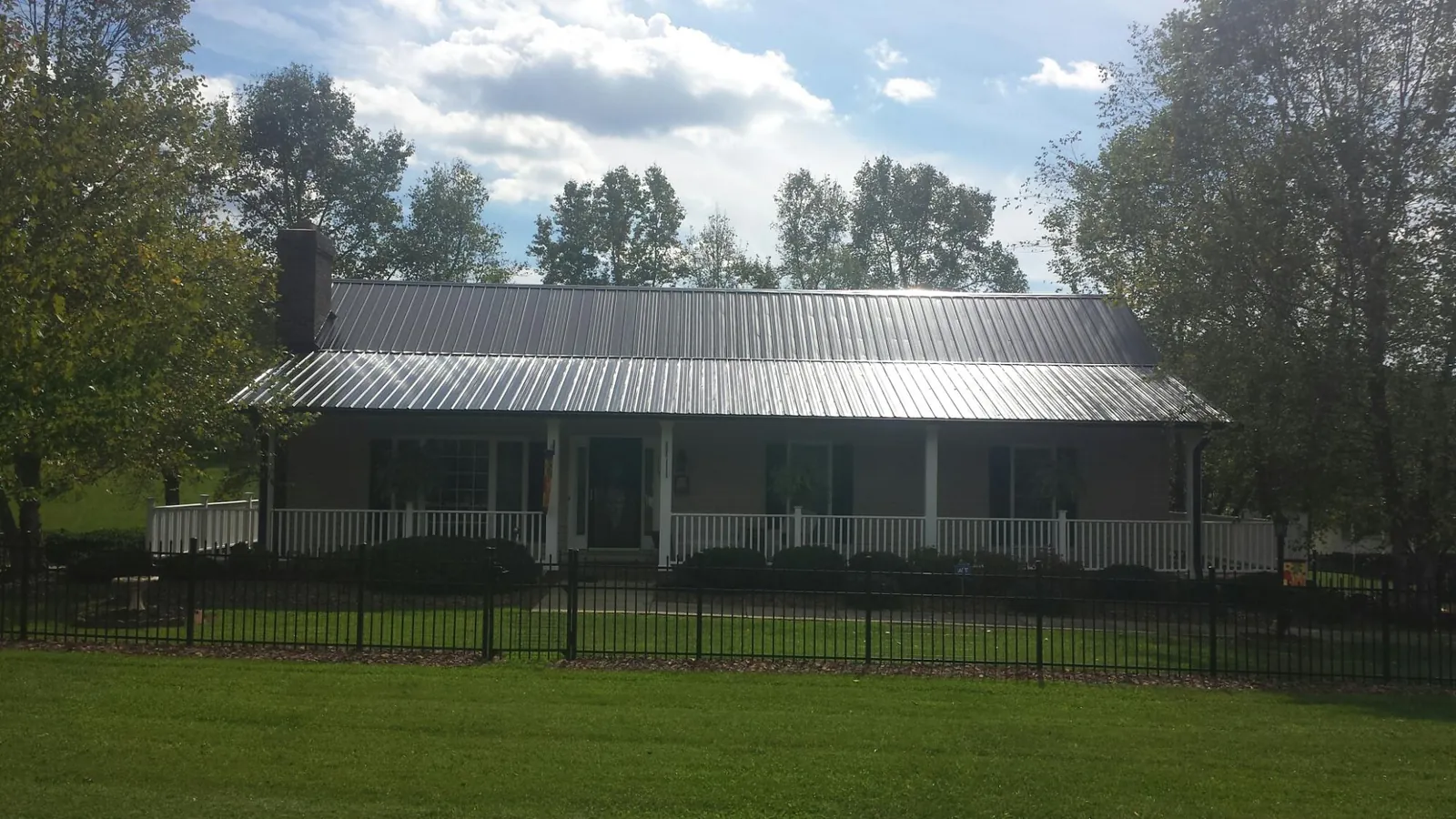 Gray metal roof on a brick ranch with a full width front porch — Gutter Guard Installation work by our crew in Cold Spring Harbor