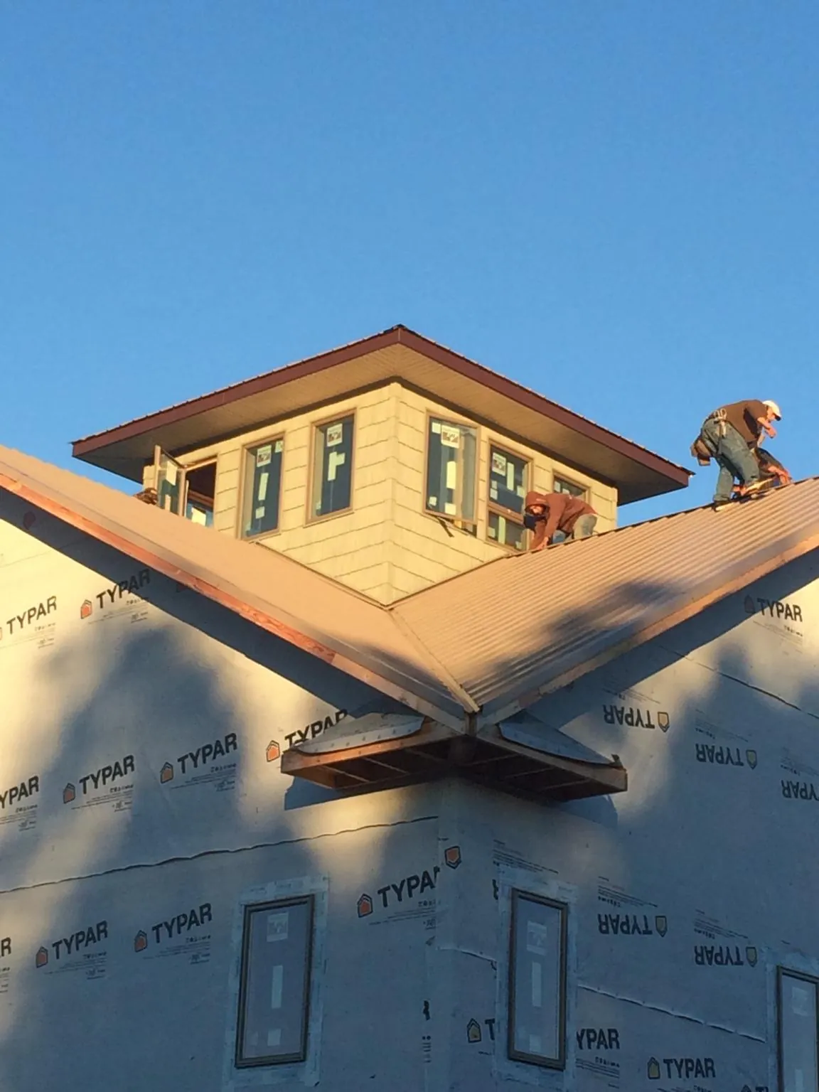 Roofers working around a rooftop cupola on a new metal roof at sunset — Roof Waterproofing in Cold Spring Harbor by Roofing Brothers
